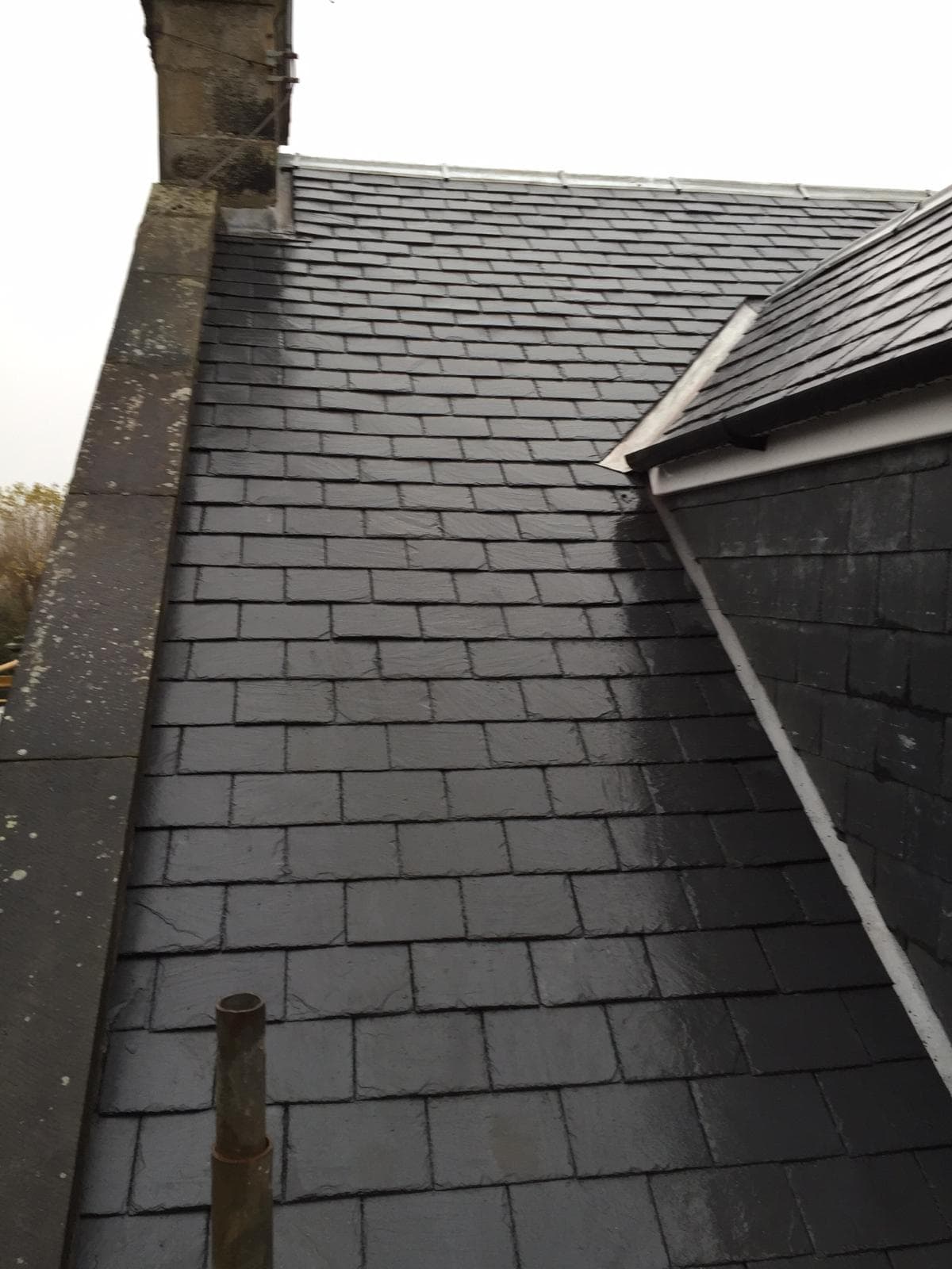 New slate roof with lead flashing at chimney abutment, overcast sky