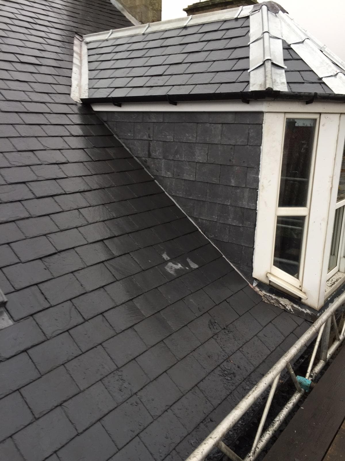 Close up of freshly laid natural dark grey slates with white aluminium flashing