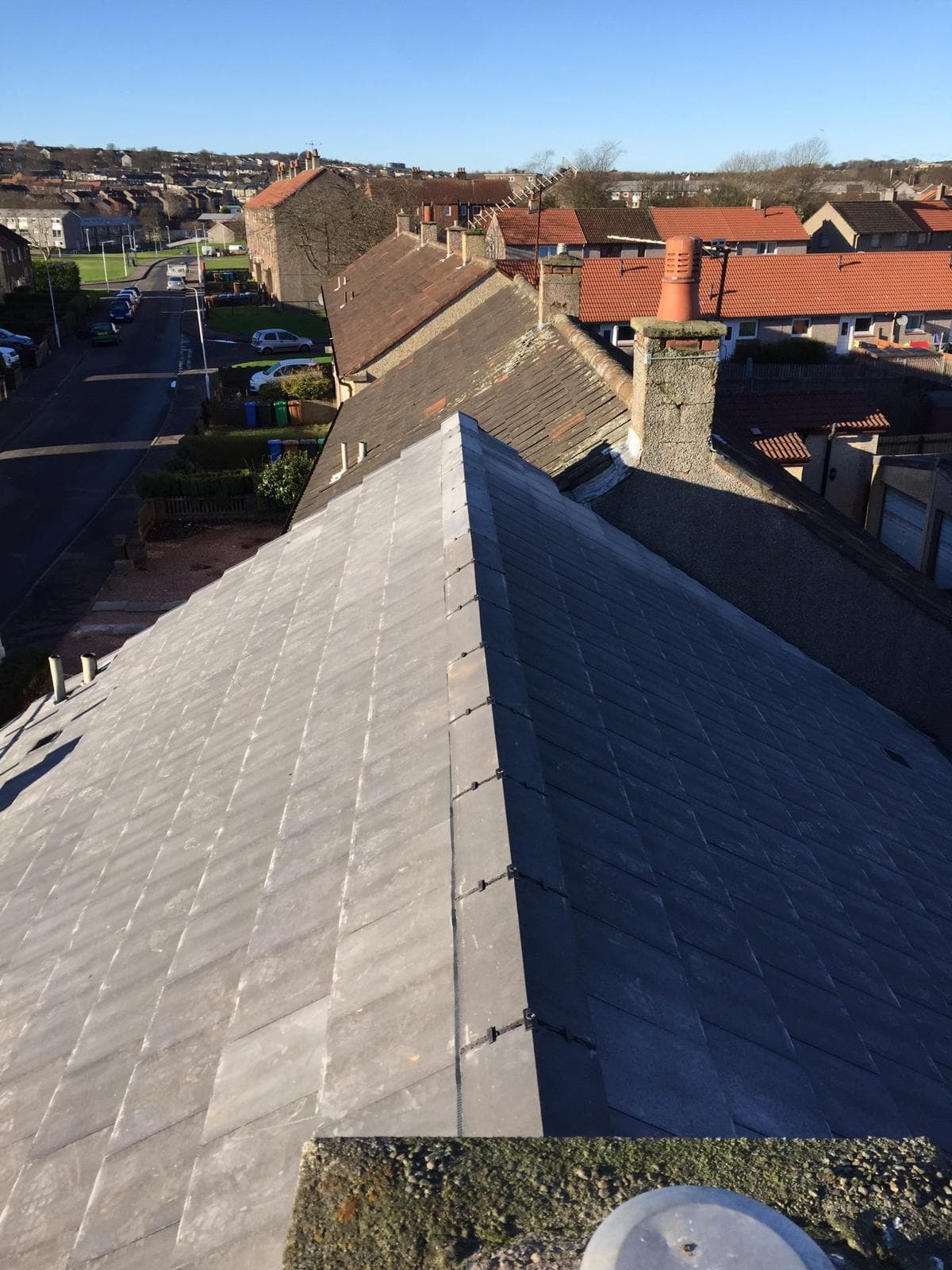 Aerial view of completed new slate hip roof over Scottish town with Firth of Forth visible
