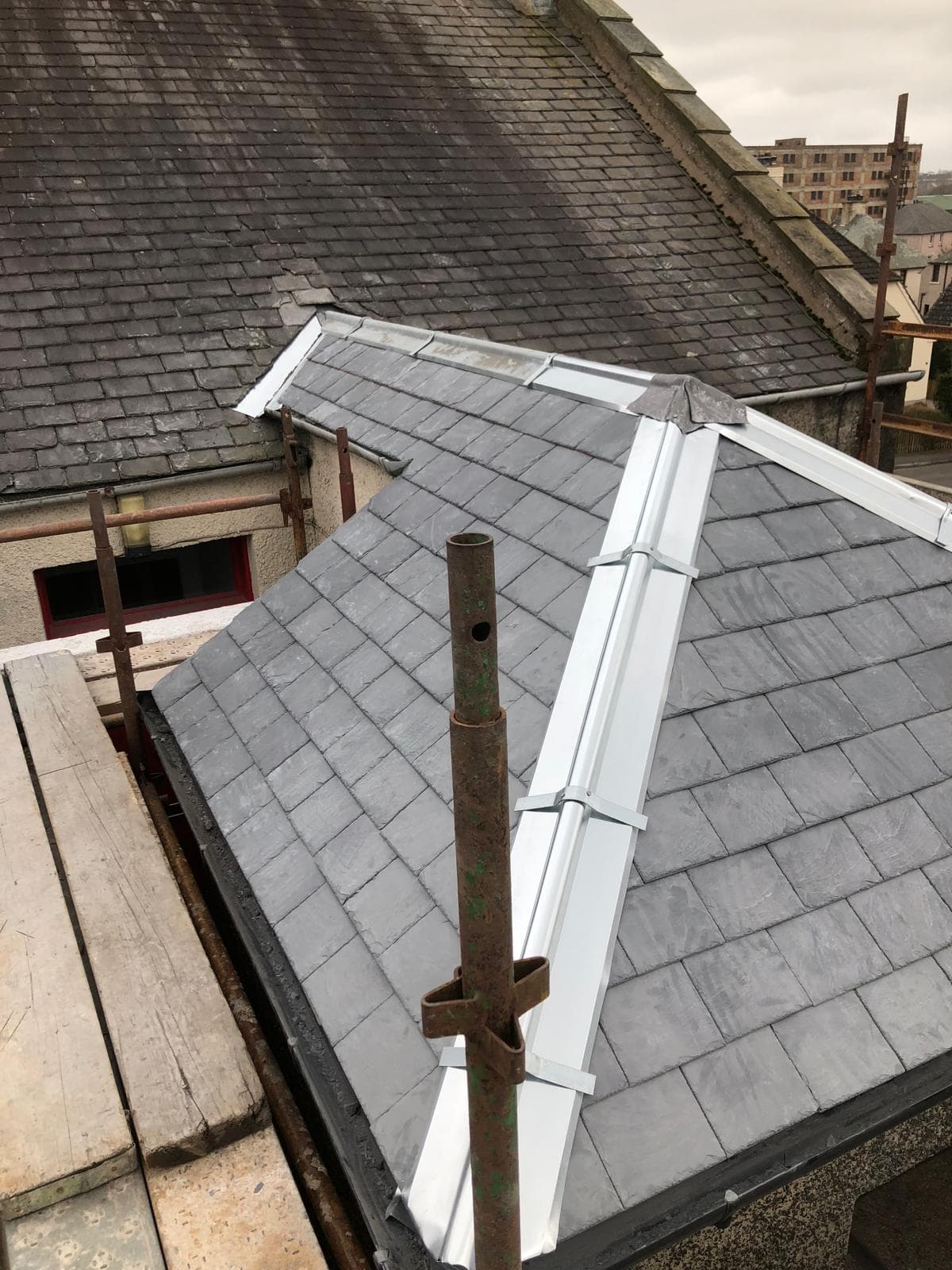 Completed slate hip roof with white fascias and lead valley, blue sky