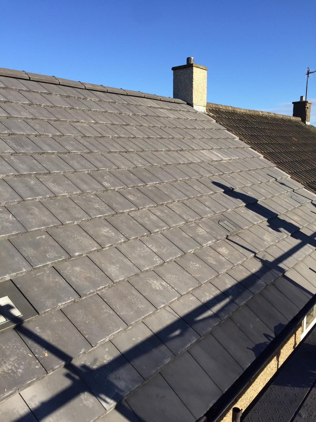 New concrete tiled roof on Scottish semi-detached house, blue sky, chimney with terracotta pot